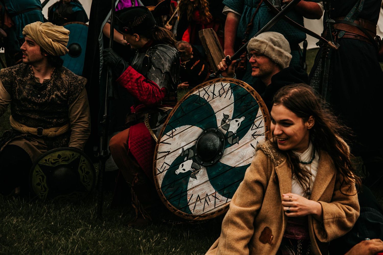 Two people embrace warmly while sitting outdoors surrounded by a crowd at a gathering.