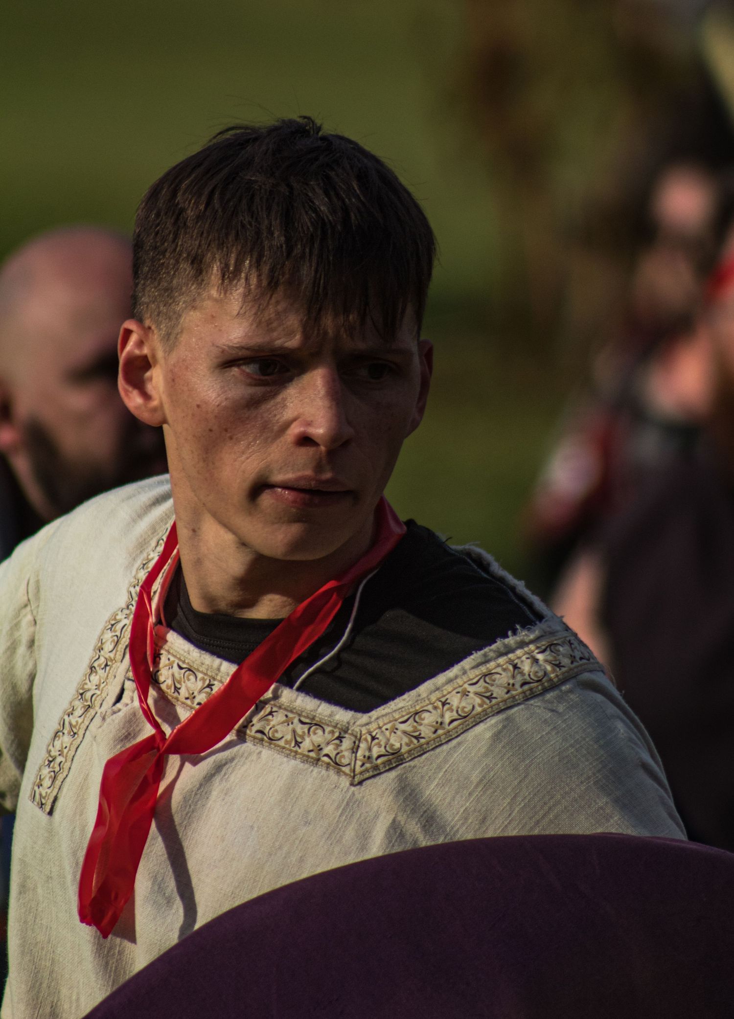 Person wearing traditional medieval costume with red necktie in natural lighting.