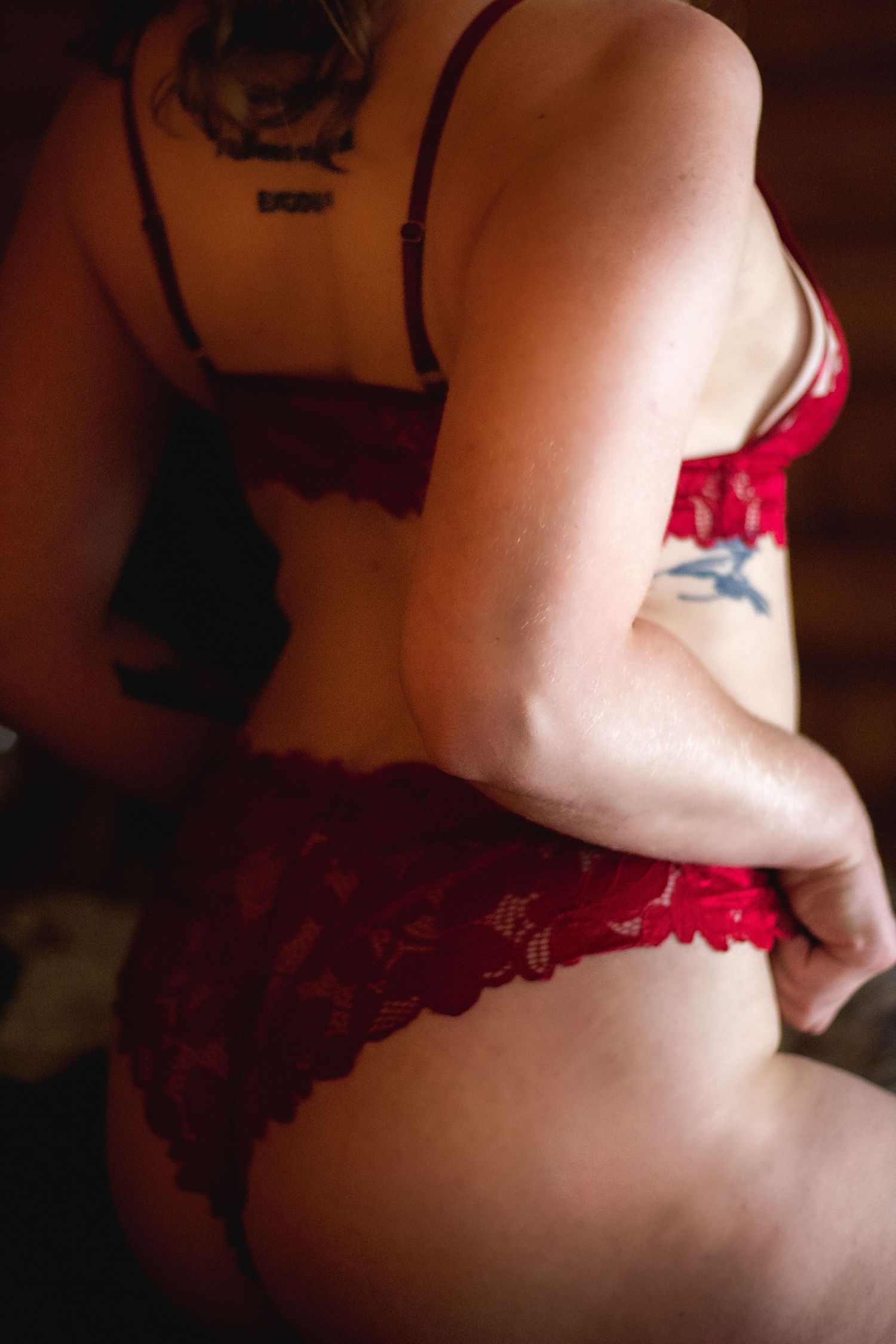 Artistic boudoir photography with soft shadows and red details.
