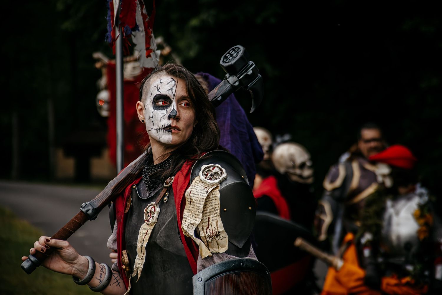 Woman in Day of the Dead skull makeup and costume holds a staff at a cosplay or Halloween parade event.