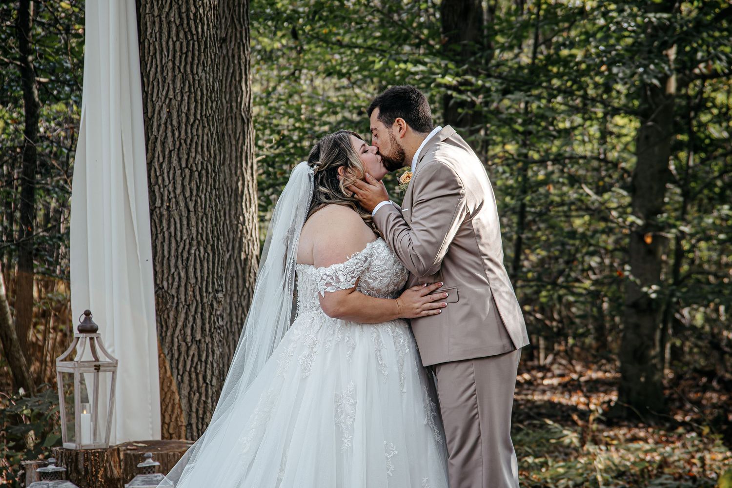 Wedding ceremony moments captured under trees with white fabric draping.