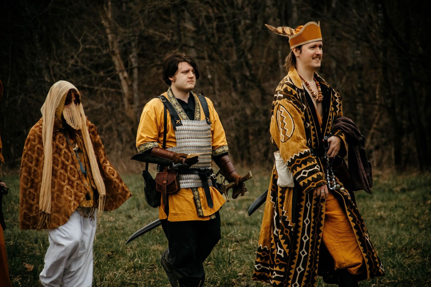 A group of friends in yellow jackets walk through an autumn forest path during golden hour.