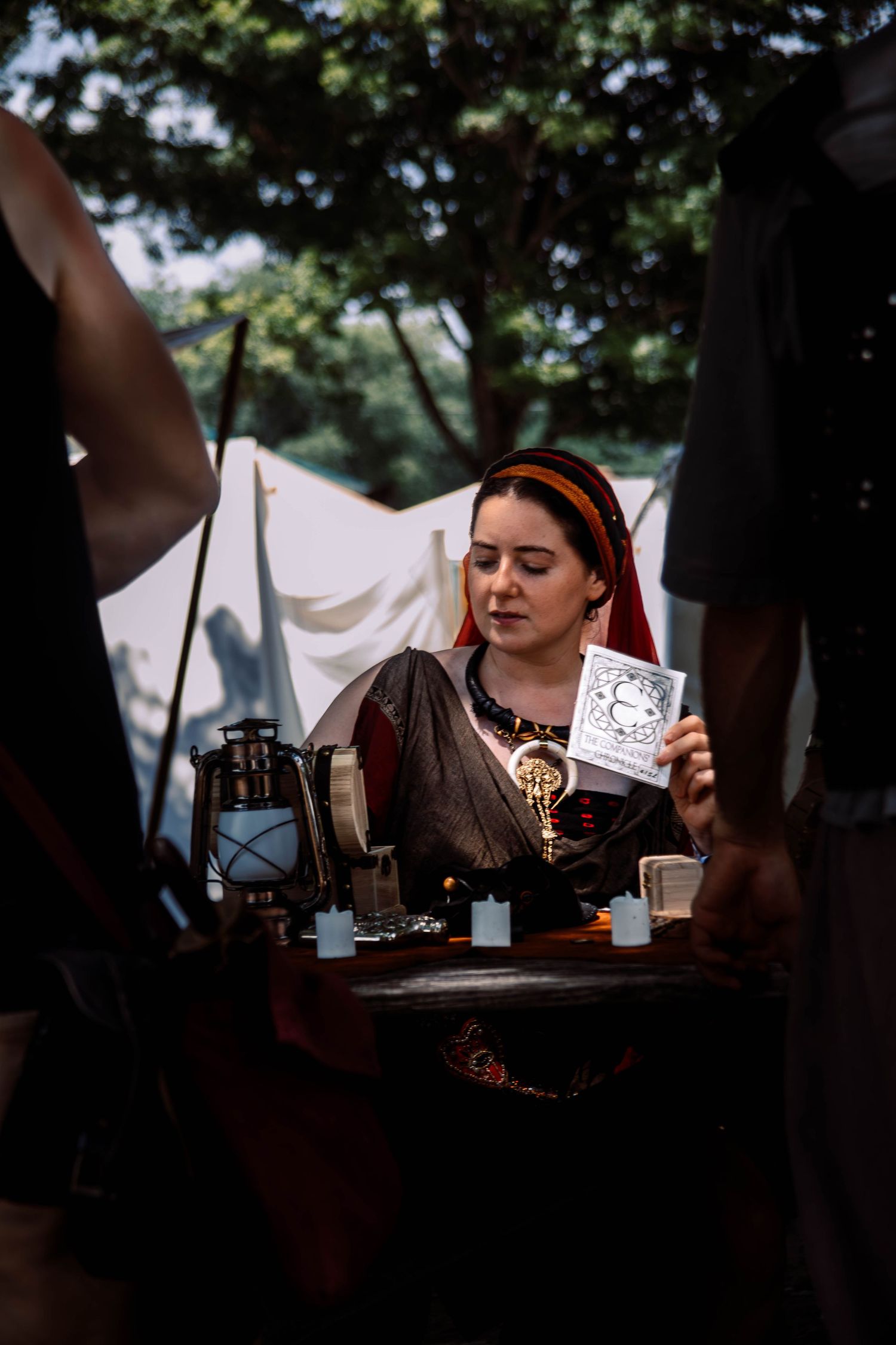 A series of dimly lit photos showing people playing cards at a table during what appears to be a medieval festival.