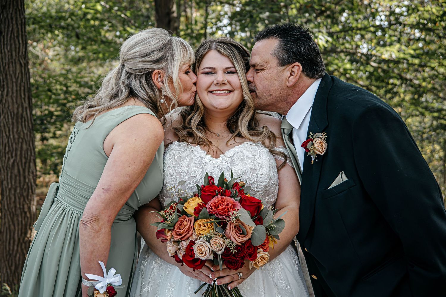 Wedding party poses outdoors with autumn foliage and trees in the background.