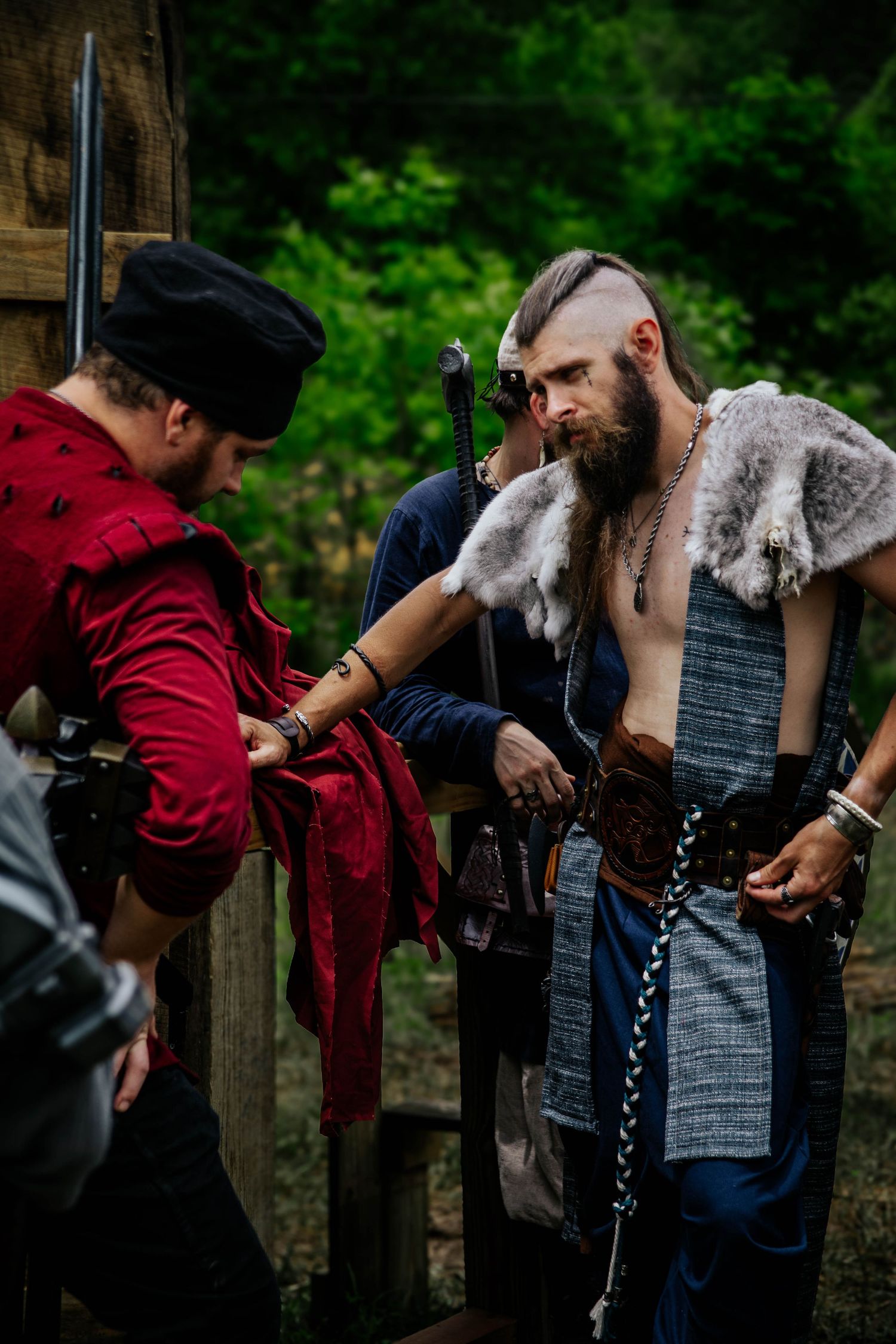 Two people in medieval costumes embrace in a romantic sequence of five progressive images against a wooden fence.