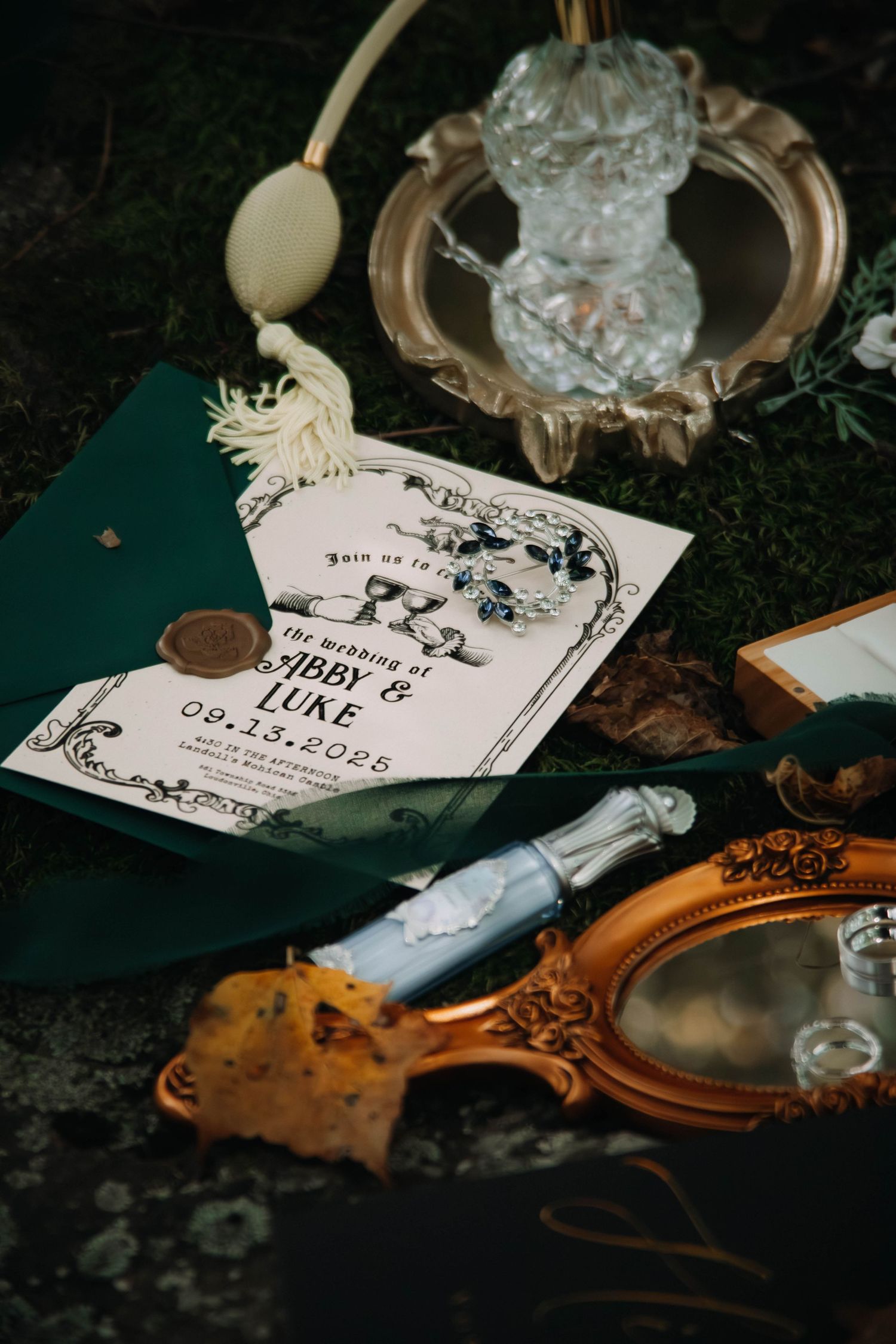 Wedding invitation with decorative floral design displayed alongside vintage accessories on dark background.