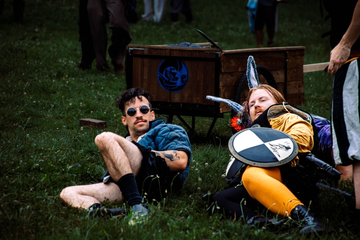 A person lies on the ground with an orange kayak nearby during an outdoor activity.