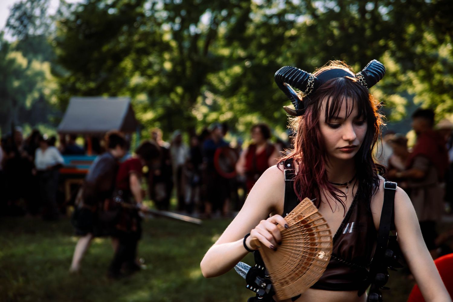 A sequence of photos showing a person with a fan dancing in a wooded outdoor setting during a festival.