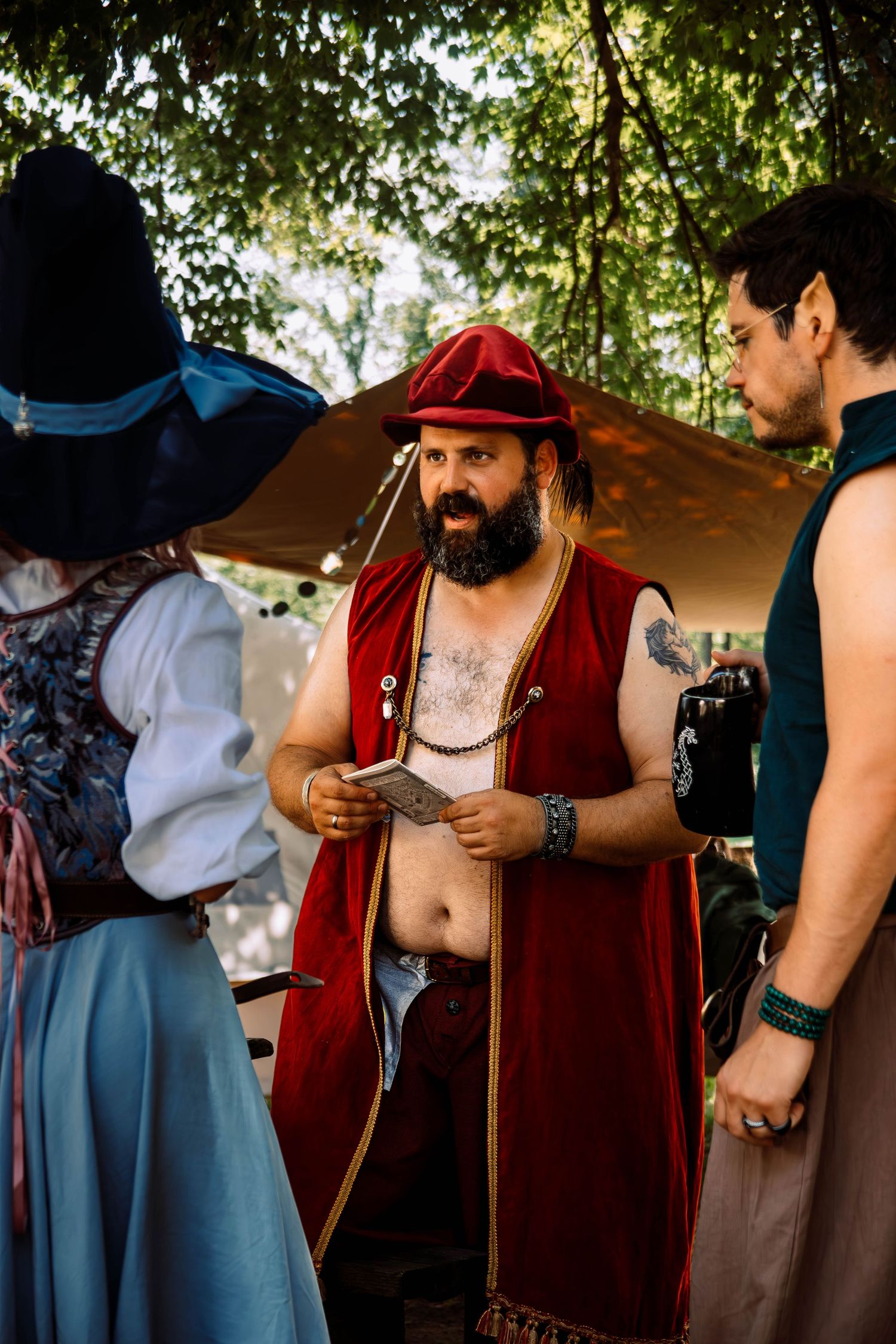 People in medieval renaissance fair costumes interact during an outdoor festival gathering.