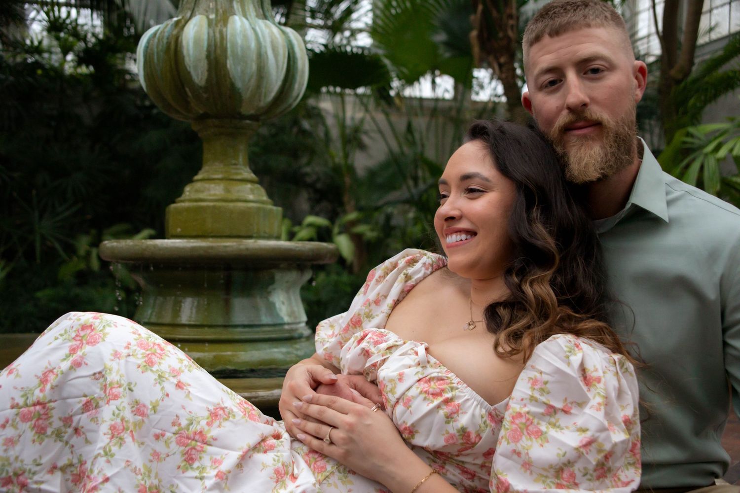 A couple shares tender moments together in a garden setting while wearing coordinated floral and casual attire.