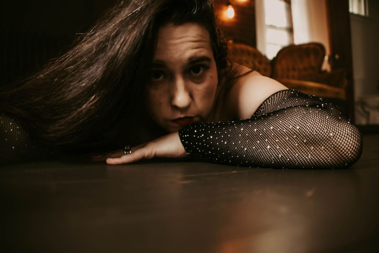 Moody boudoir portrait with warm candlelight and dramatic shadows.