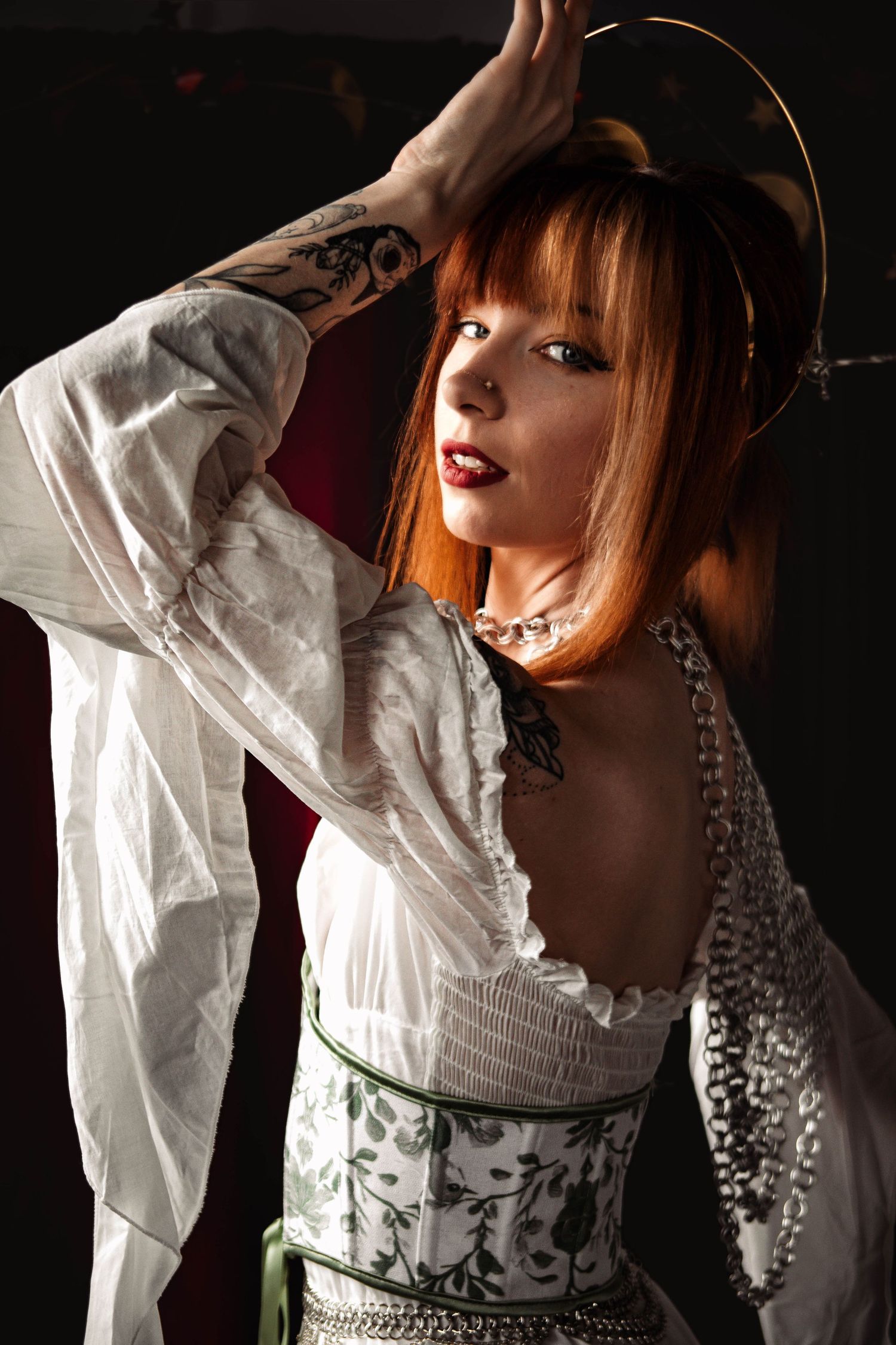 Dramatic portrait series with white ruffled clothing and pearl necklace in low light.