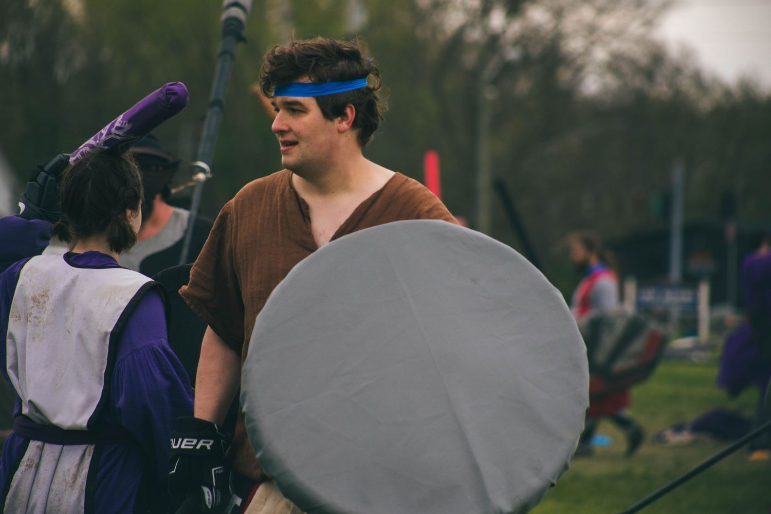 Participants in medieval costumes line up during an outdoor historical event.
