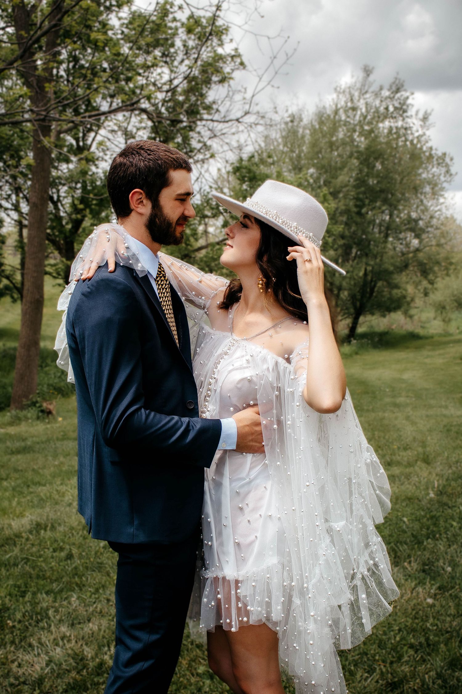 A romantic couple shares intimate moments in a natural outdoor setting with the bride wearing a delicate lace dress.