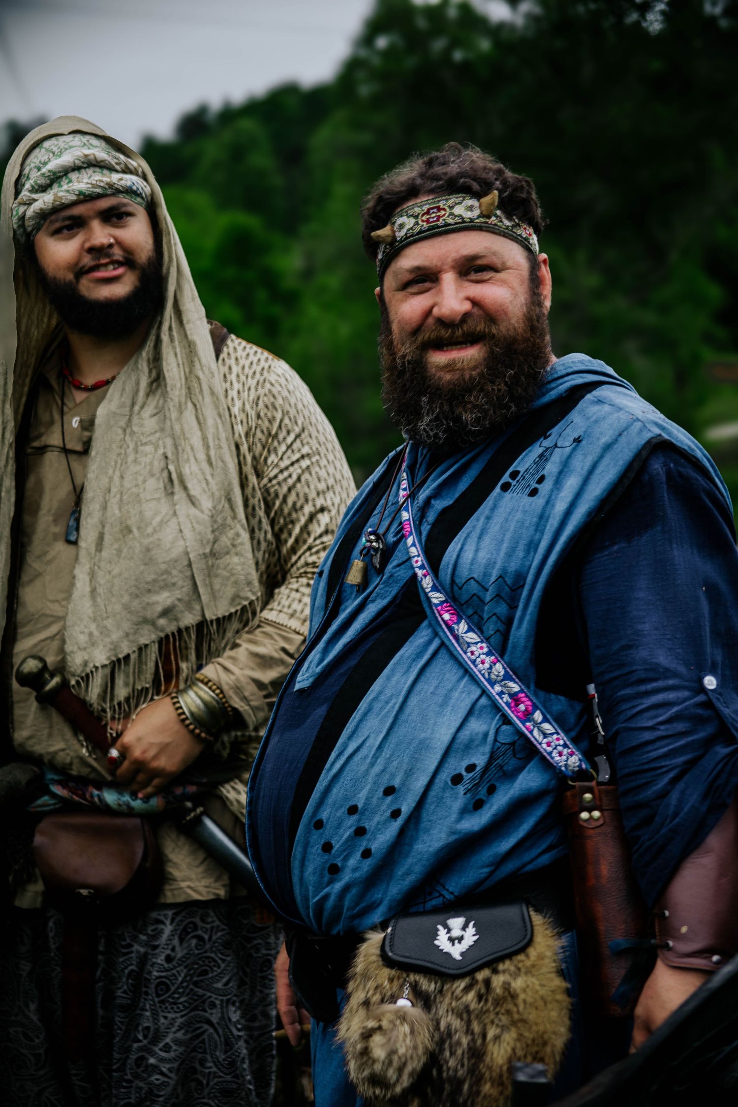 Reenactors in medieval clothing and fur accessories pose together outdoors.