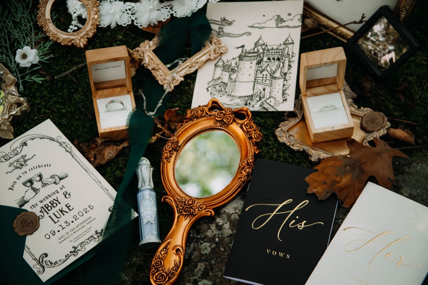 Wedding details flatlay with vintage mirror, invitation cards and decorative elements on dark background.