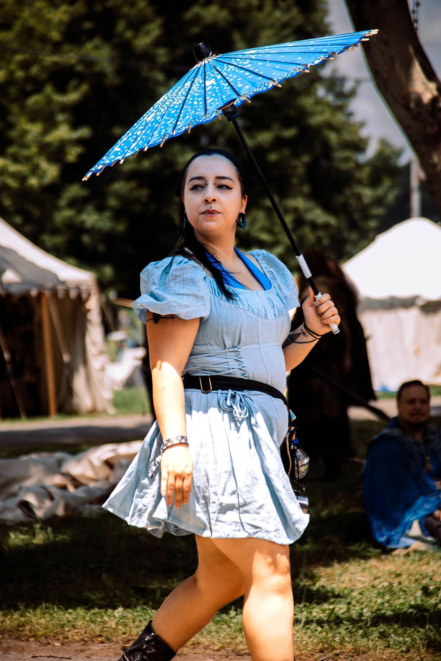 A sequence of artistic shots showing someone posing outdoors with a bright blue parasol in summer sunlight.