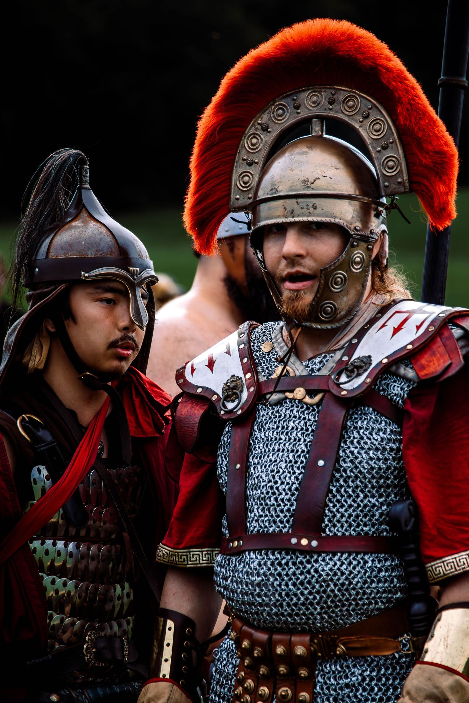 Historical reenactors wearing Roman centurion armor with red plumes and chainmail demonstrate ancient military formations.
