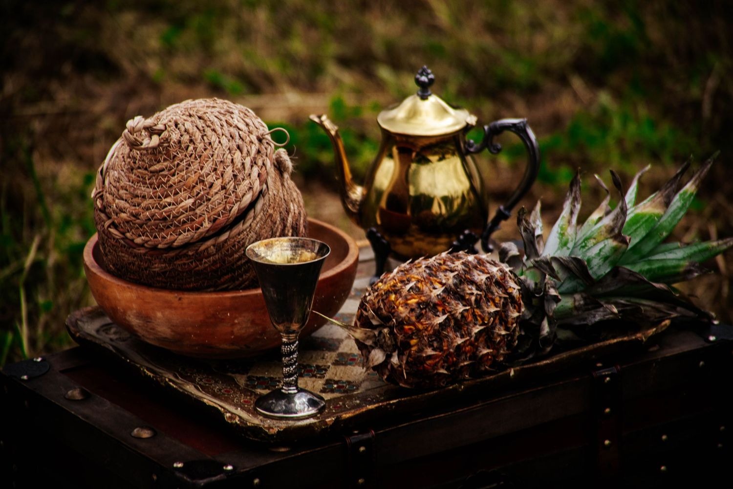 Moody candle centerpiece with natural elements like pinecones and greenery arranged on a rustic wooden tray.
