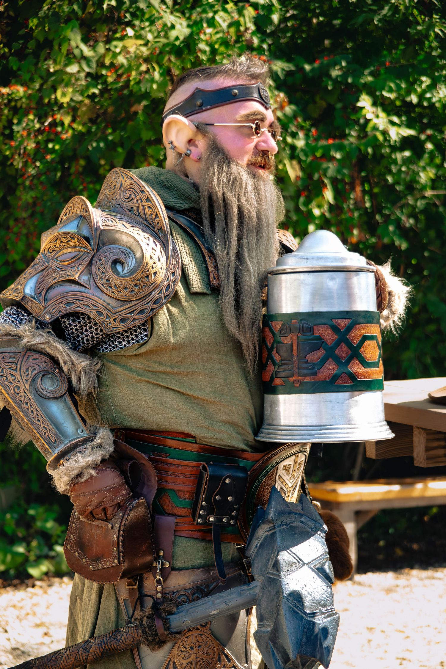 A series of photos showing a person in medieval Viking costume with an ornate leather shoulder piece carrying a metal stein.