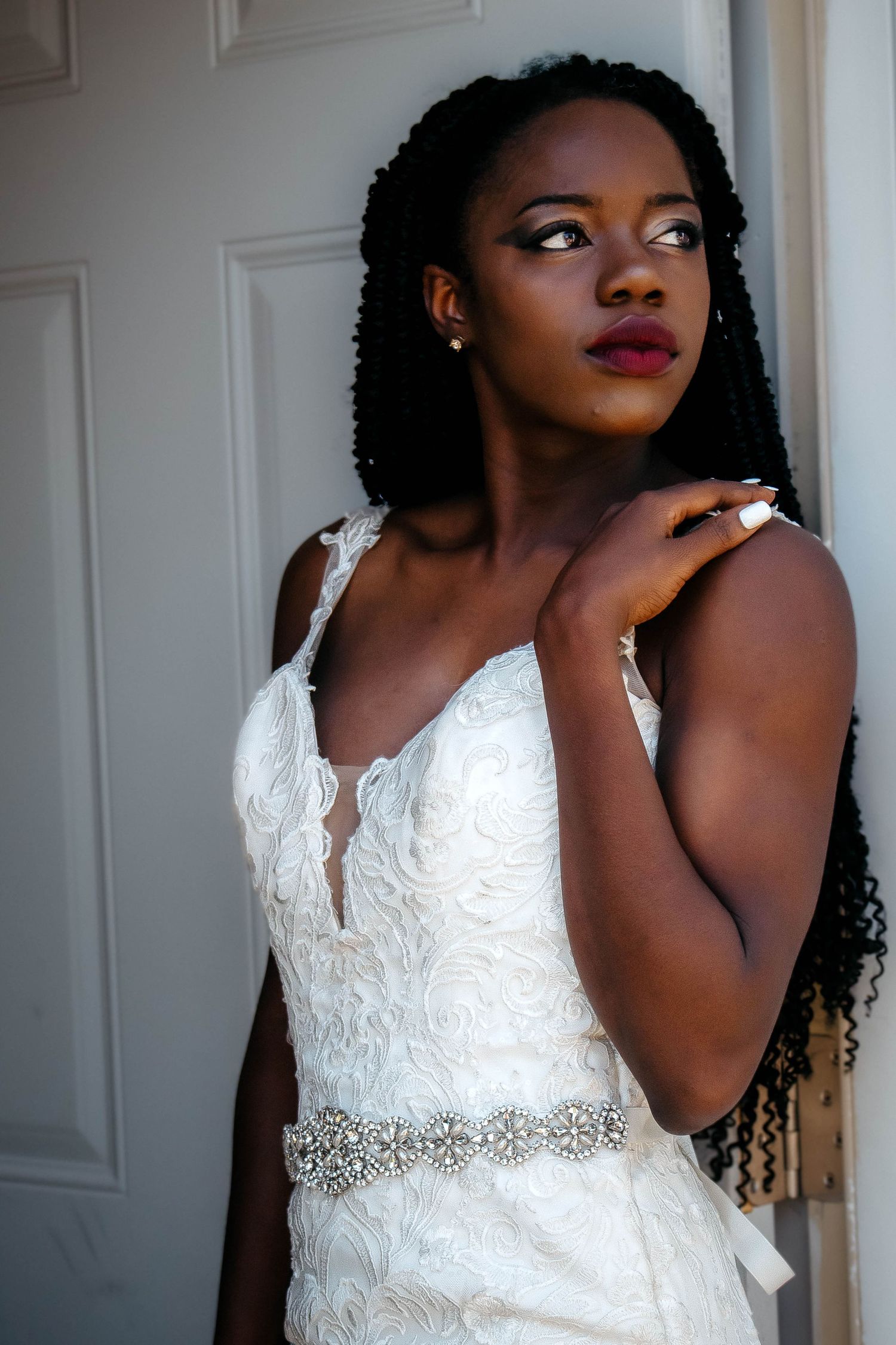 A bridal portrait series showing a white lace wedding dress with beaded belt detail against a light background.