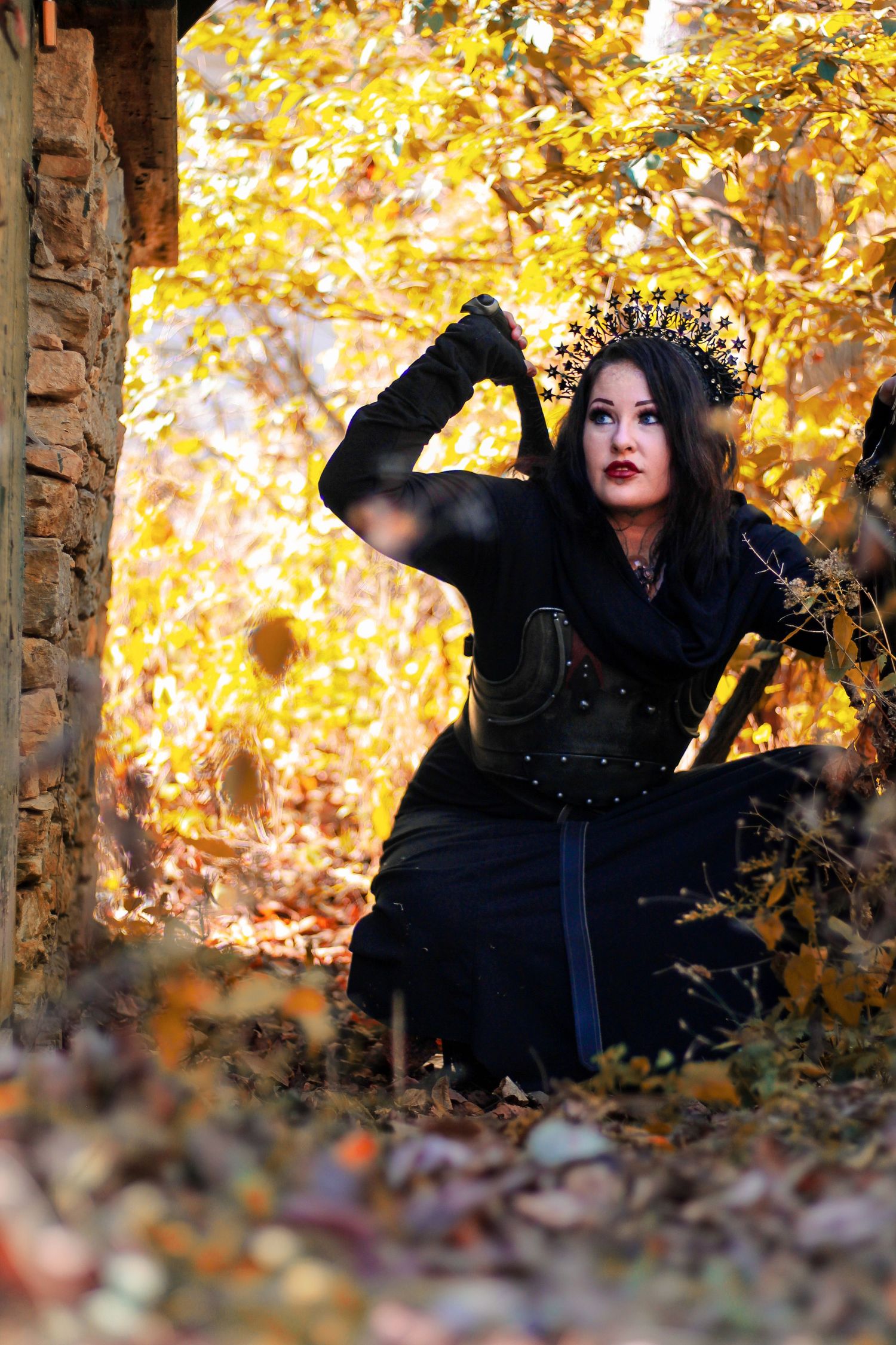 Dramatic autumn photoshoot with black clothing against golden fall foliage.