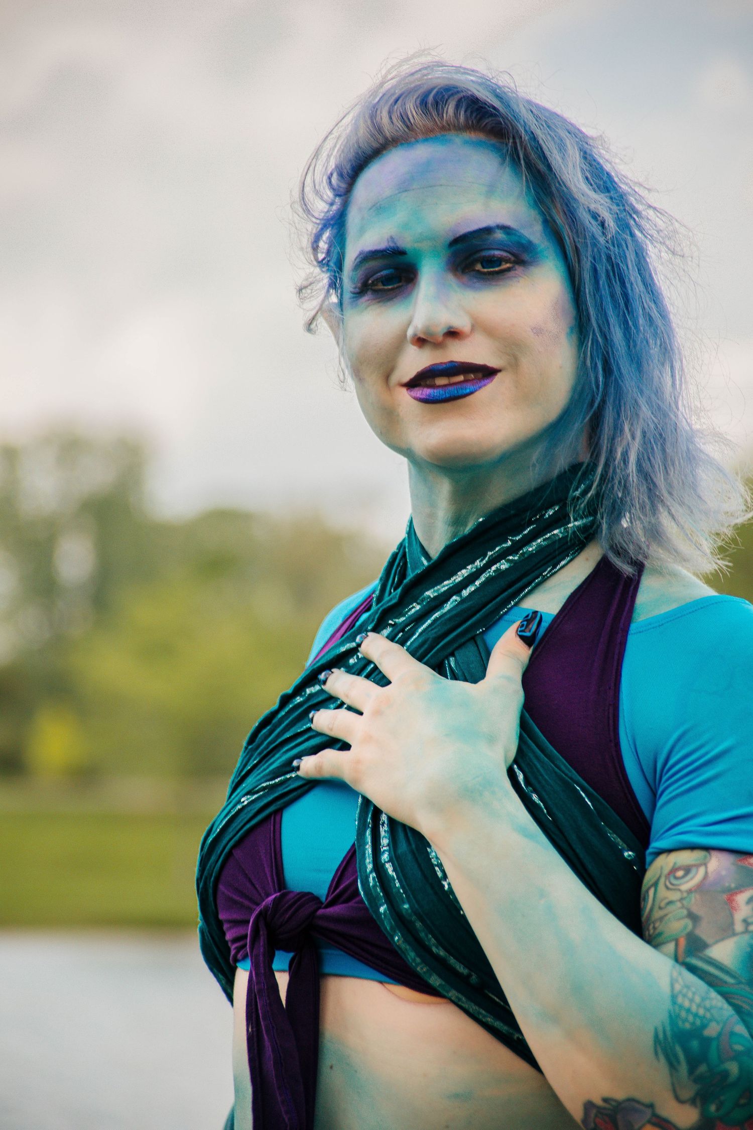 Alternative fashion shoot with blue hair, dramatic makeup, and teal clothing.