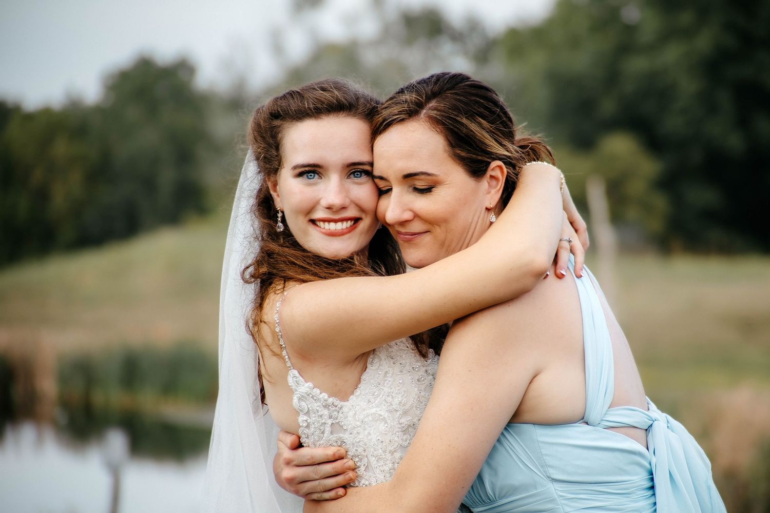 Two people embrace in a romantic outdoor photoshoot wearing blue and white outfits.