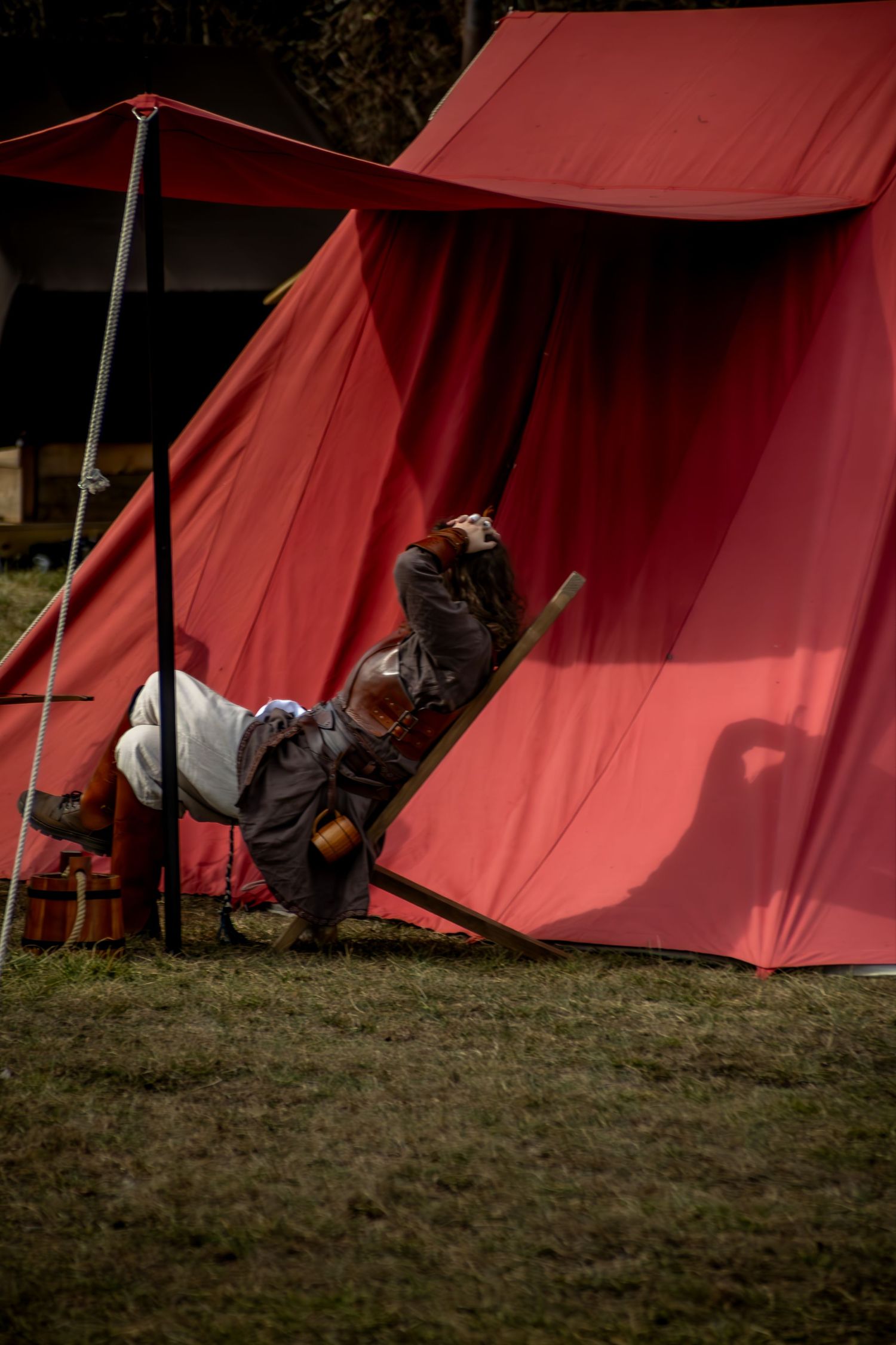 A series of red canvas tents lined up at a campsite showing different angles of their setup and structure.