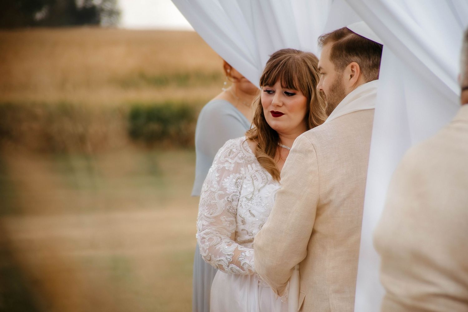 A romantic wedding couple shares an intimate moment in an outdoor setting with soft natural lighting.
