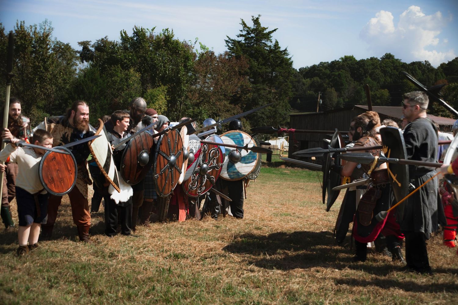 A crowd of people gathered outdoors at a rural event with vintage tractors and farming equipment on display.