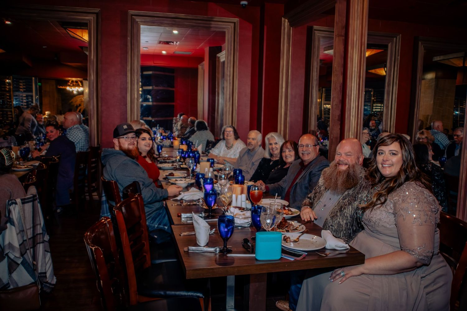 Large group of people seated at a long dining table in an elegant restaurant, enjoying a formal dinner together.