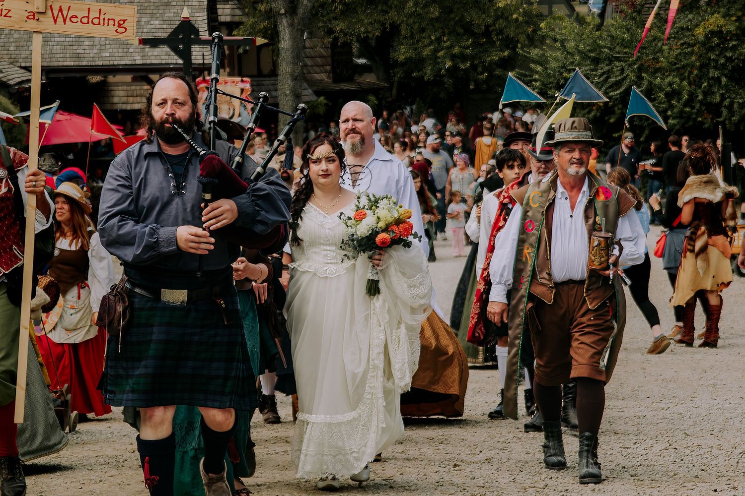 A crowd of wedding guests gathers outdoors in a courtyard during a festive celebration.