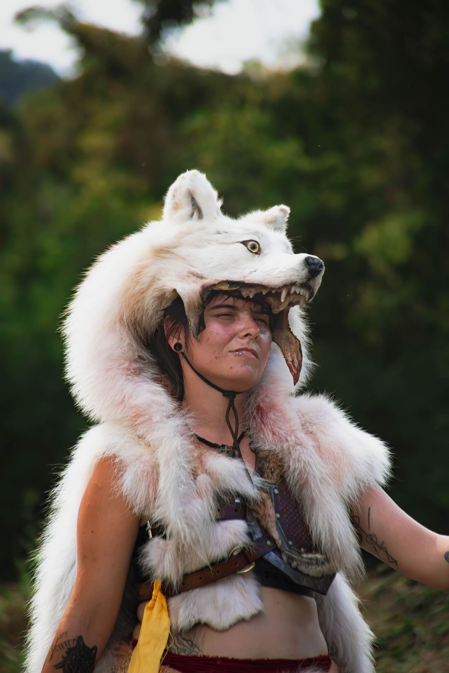Four sequential photos showing someone wearing a furry white hood and helmet in an outdoor nature setting.