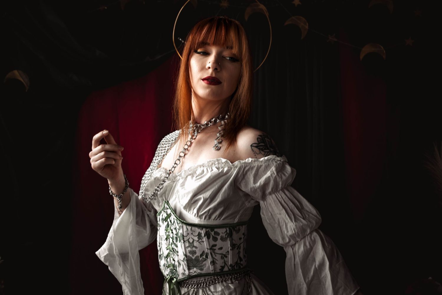 Person in a white vintage-style dress with lace details against a dark background.