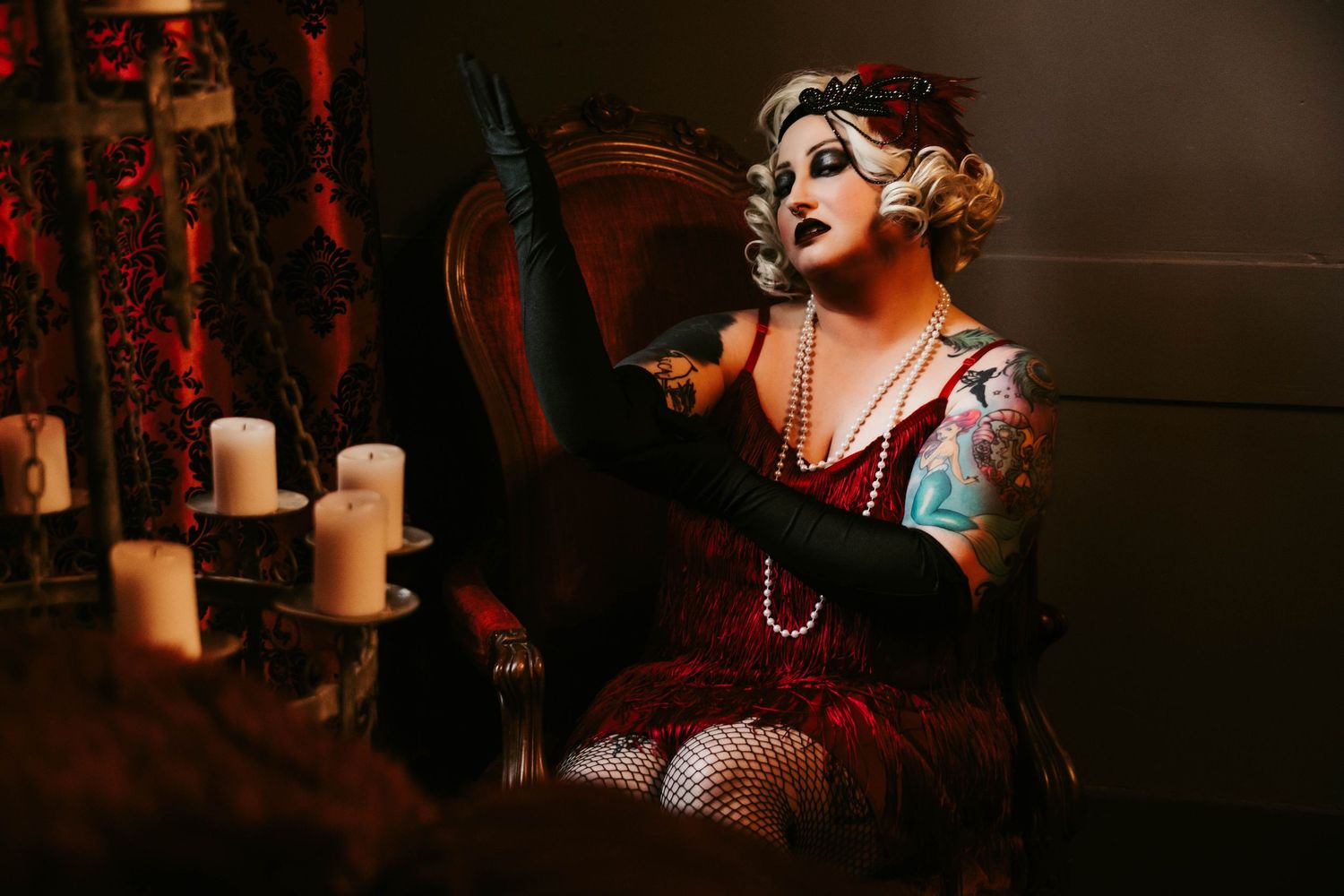 Vintage cabaret performer in fishnet stockings singing on stage with lit candles in background.