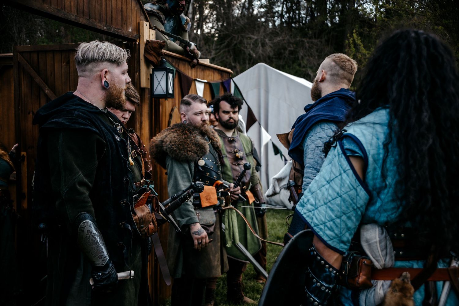 Group of people dressed in Viking medieval costumes gathered outdoors at a historical reenactment event.