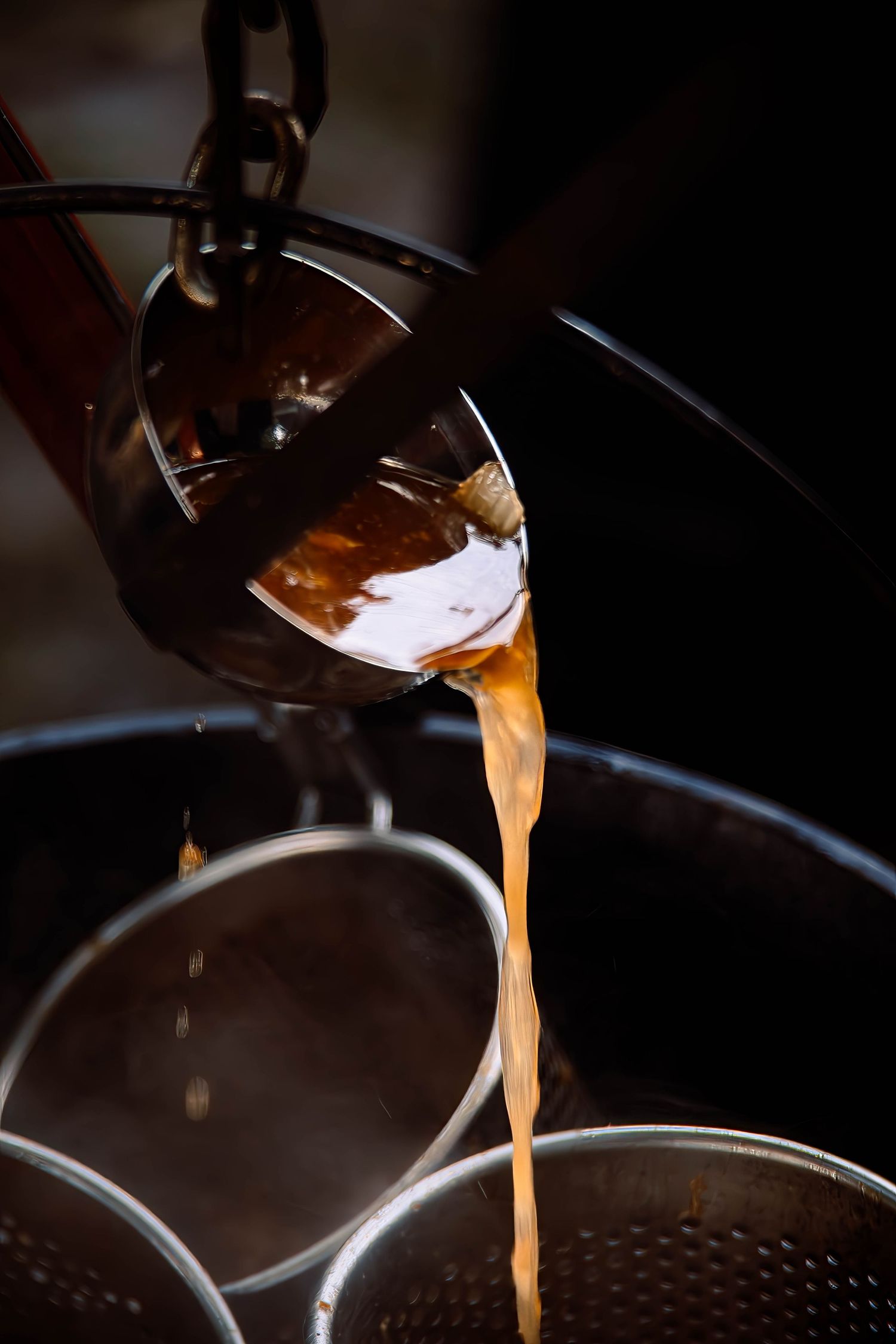 Fresh espresso shot pouring from a professional coffee machine portafilter into a dark cup.