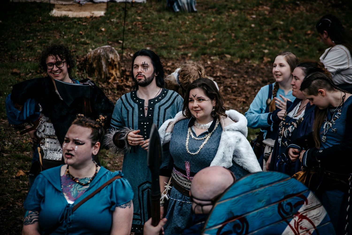 Group of people in medieval Renaissance costumes gathered outdoors at a historical reenactment event.