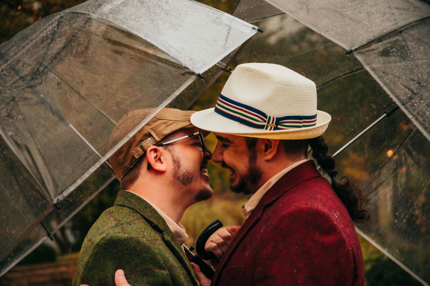 Two people in hats share a romantic kiss outdoors during golden hour.