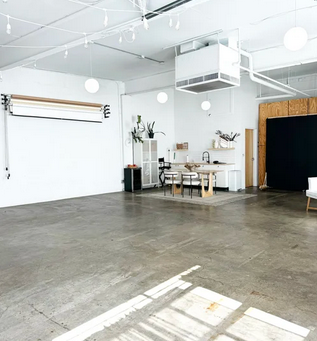 Large open industrial studio space with concrete floors and white walls featuring minimalist design elements.