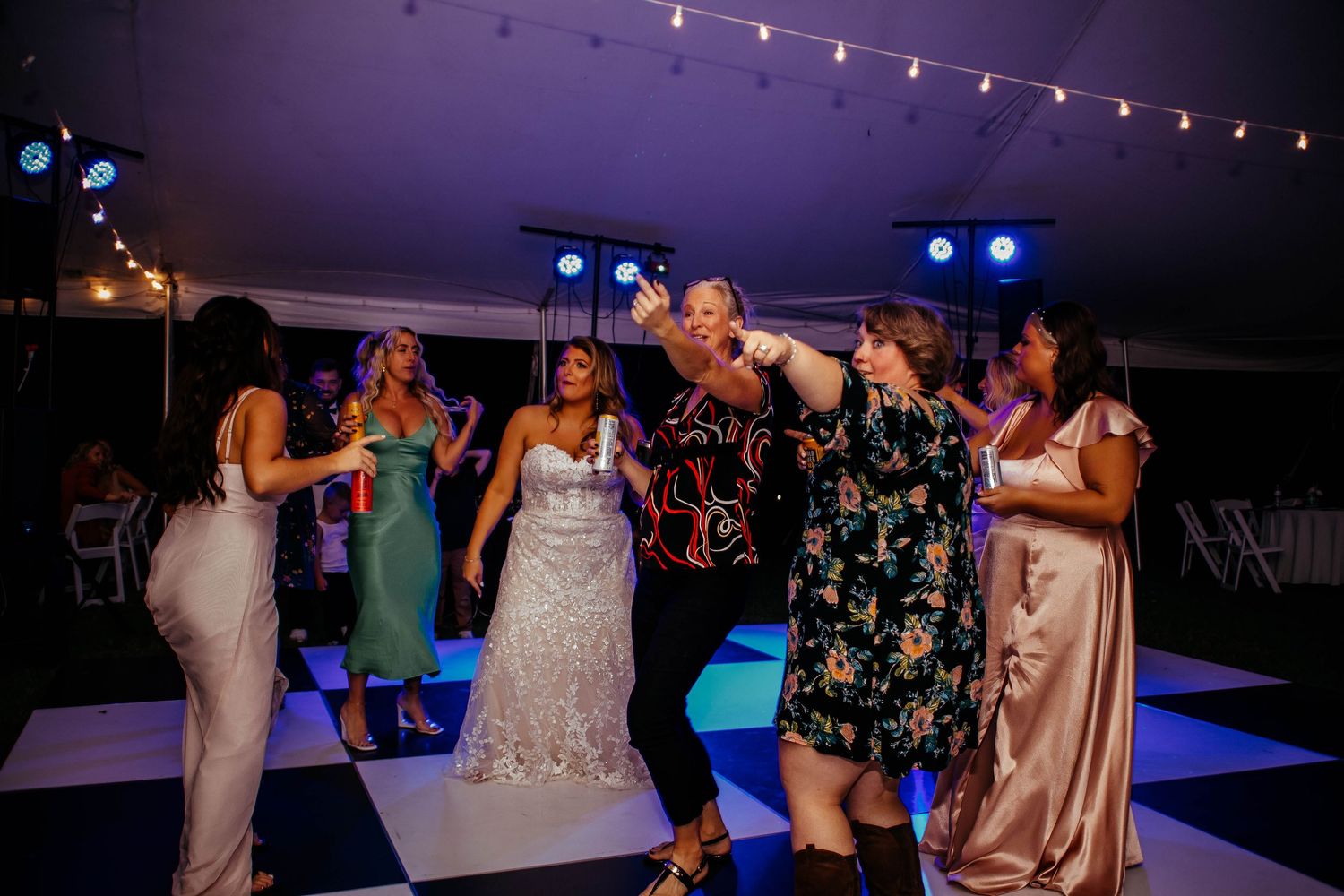 Bride and guests dancing joyfully on a black and white checkered dance floor at a wedding reception.