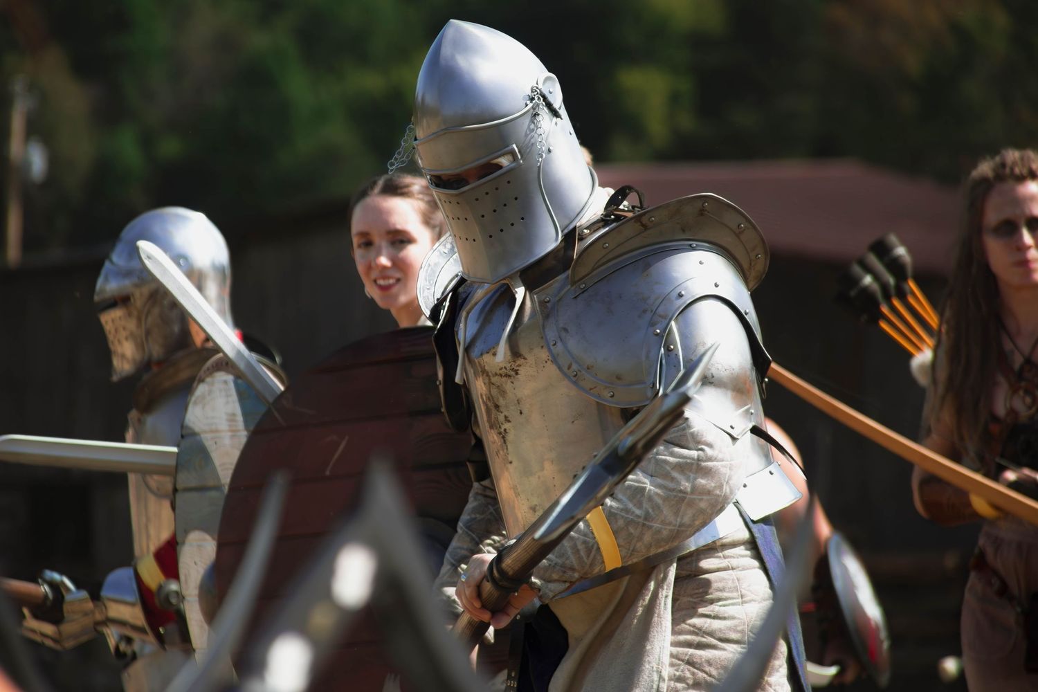 Medieval knights in full armor engage in combat during a historical reenactment battle scene.
