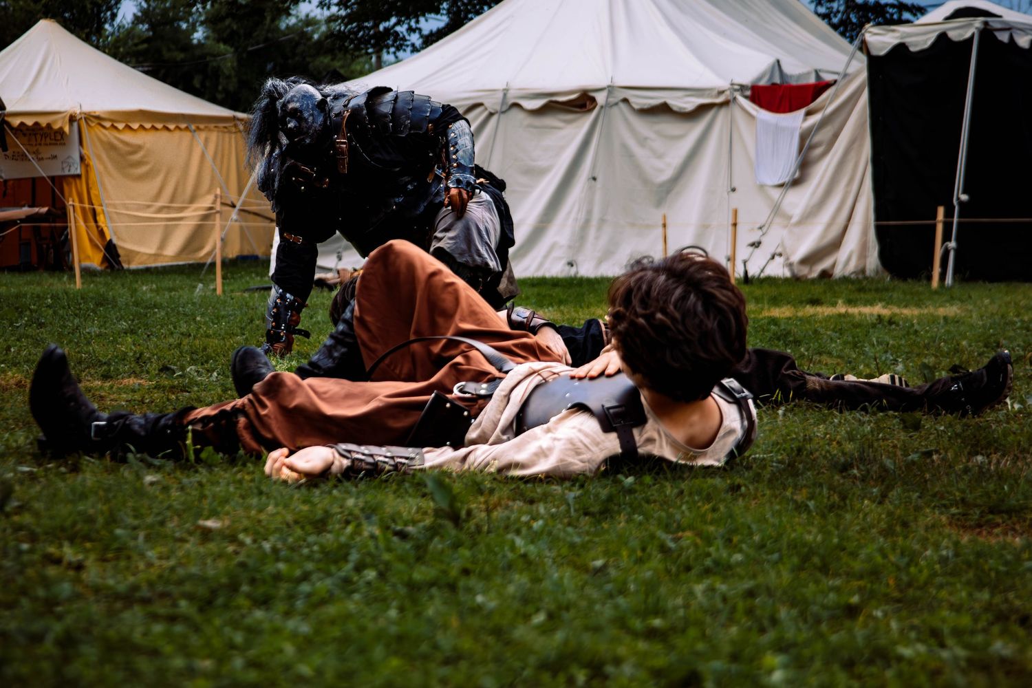 A row of white canvas tents set up on grassy field during a historical reenactment event.