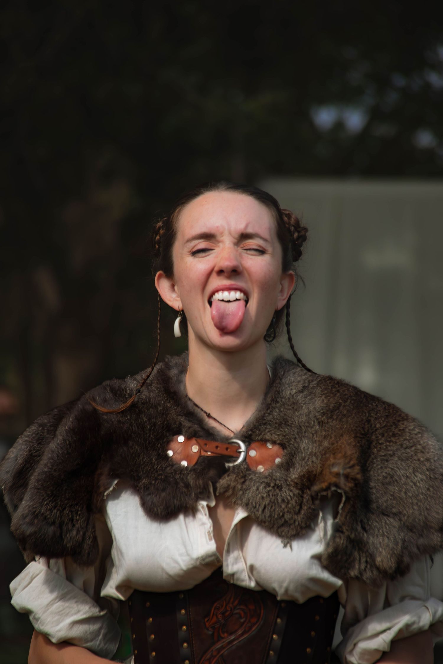 A sequence of playful expressions showing someone wearing a brown fur collar and white blouse sticking out their tongue.