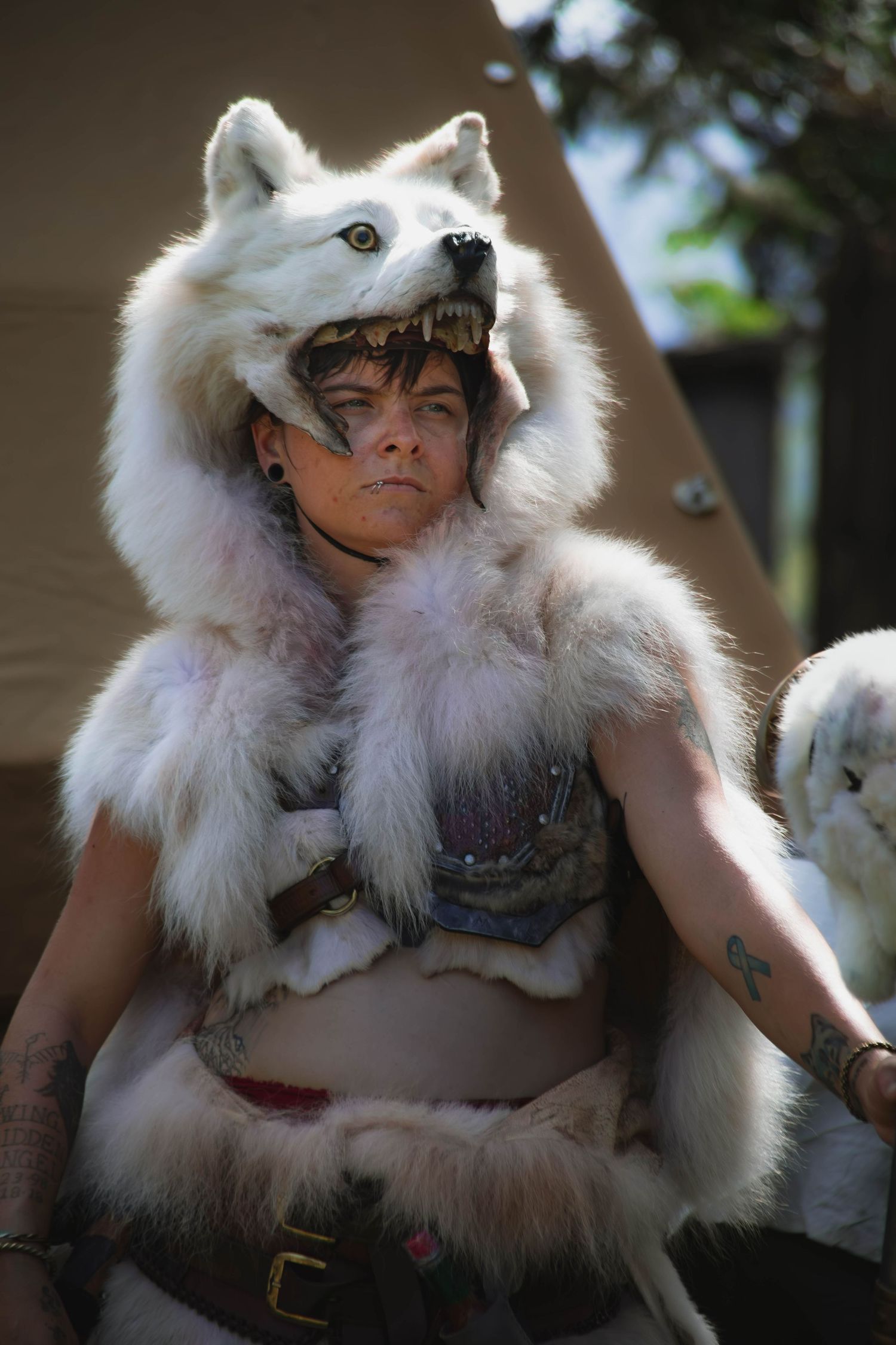 Warrior wearing white fur cloak and medieval armor in outdoor setting.