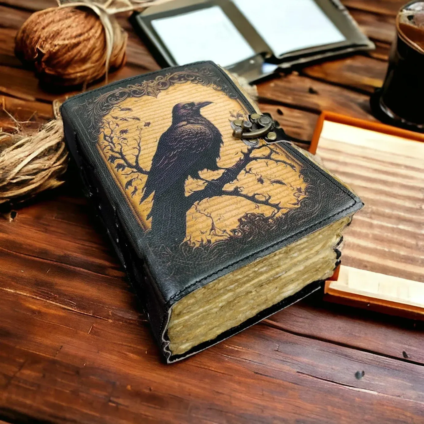 An antique black leather book with a raven silhouette design sits on a wooden surface in dramatic lighting.