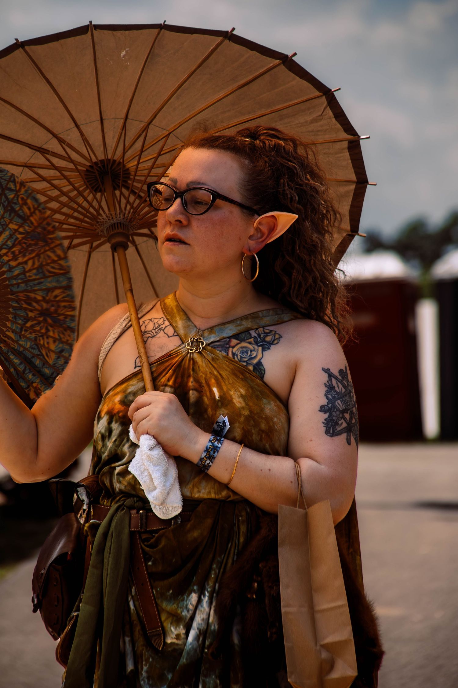 A person with red hair poses with a vintage parasol against a cloudy sky in an artistic portrait series.