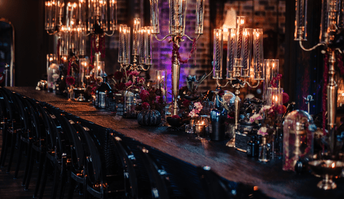 A cozy bar interior with warm lighting, glowing candles, and dark wood furnishings creating an intimate atmosphere.