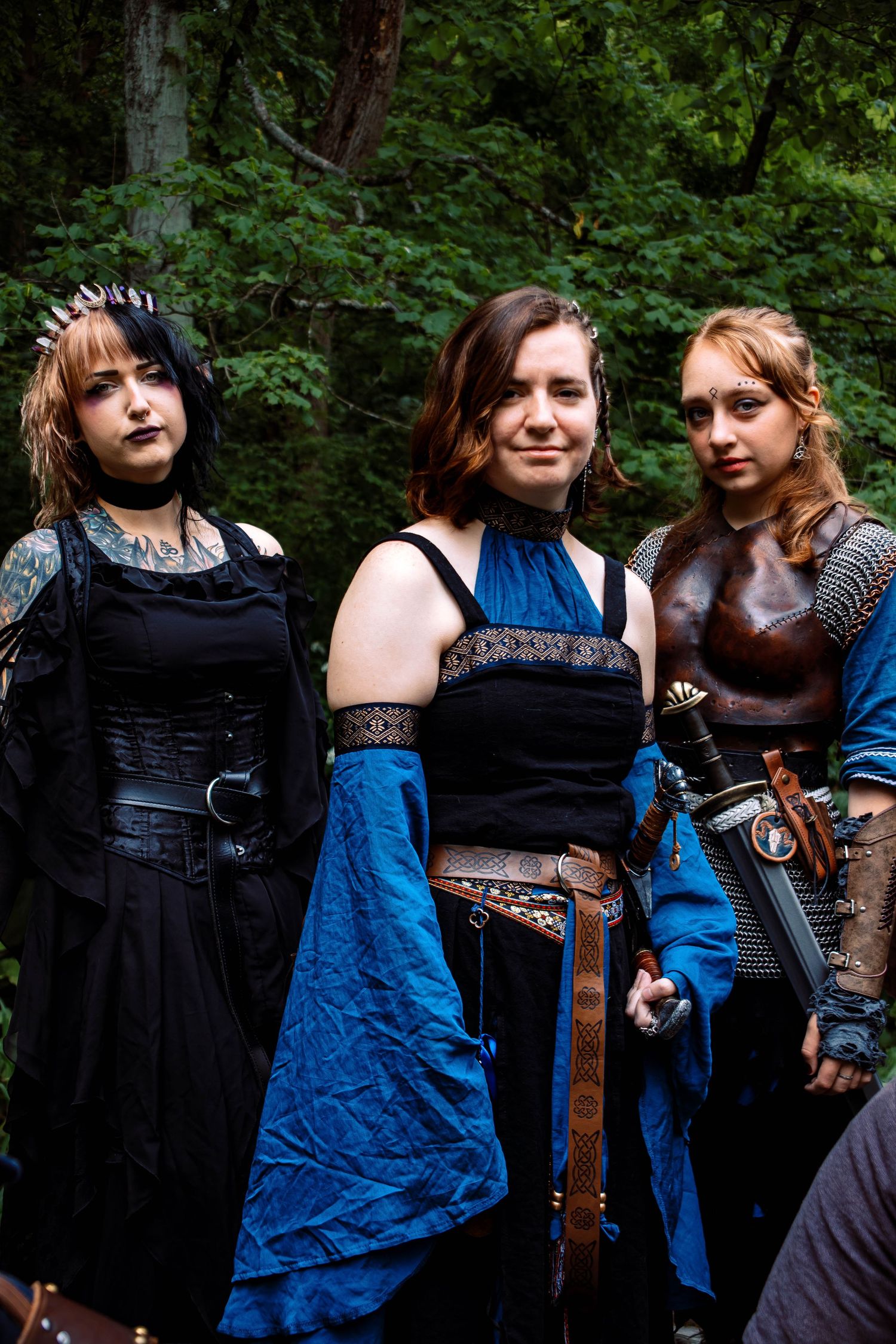 A group in medieval fantasy costumes poses together in a wooded outdoor setting.